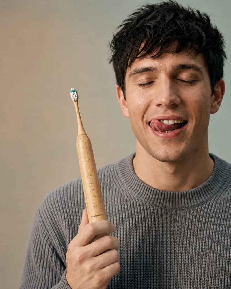 Man smiling while brushing his teeth with the bamtoo bamboo toothbrush