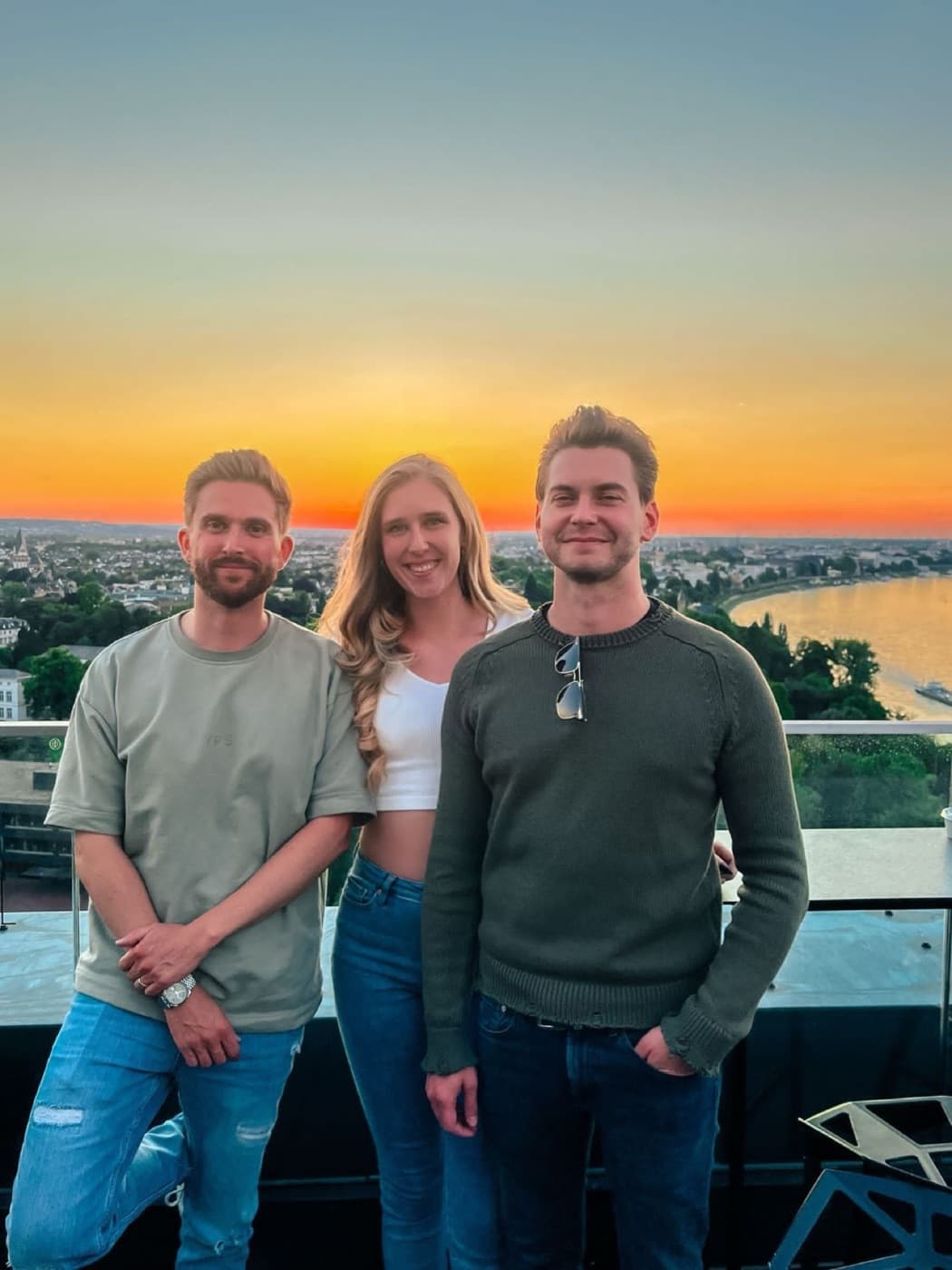 Three team members on a rooftop at sunset