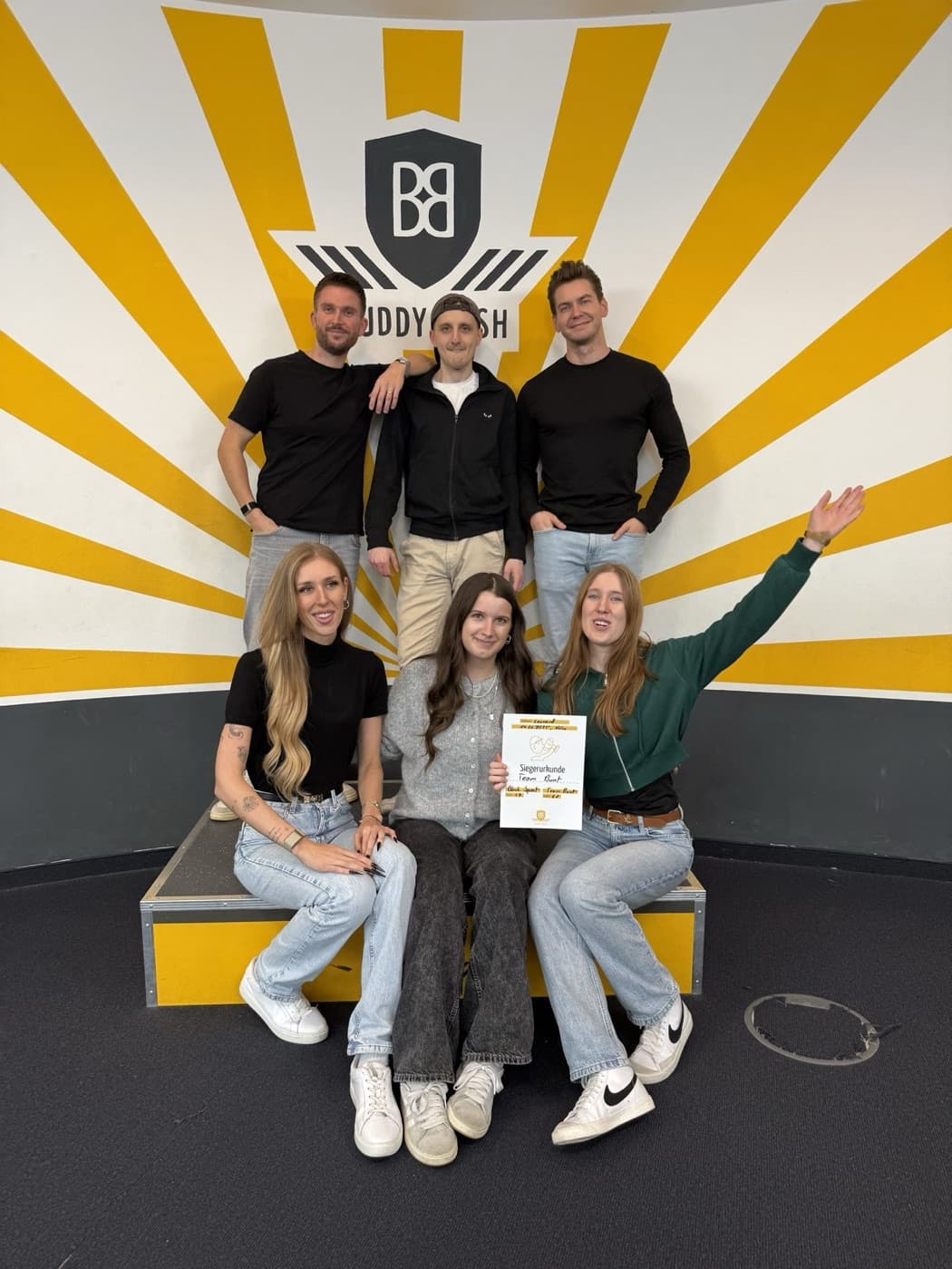The team at a team event in front of a yellow wall